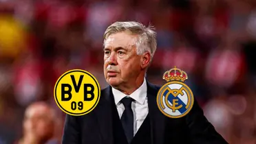 Carlo Ancelotti looks onto the pitch as the Borussia Dortmund and Real Madrid badges are below him.