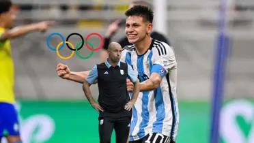 Claudio Echeverri celebrates a goal for Argentina while Javier Mascherano looks concerned and the Olympics icon is near them. (Source: Getty Images, Capodelsur X)