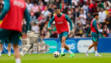 Cristiano Ronaldo dribbles with the ball while training with Portugal; a stack of cash is next to him.