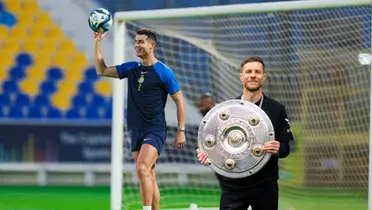 Cristiano Ronaldo holds the ball with one hand wearing a training Al Nassr kit while Xabi Alonso holds the Bundesliga title.