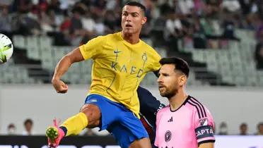 Cristiano Ronaldo looks at the ball while wearing the Al Nassr jersey and Lionel Messi stares while wearing the Inter Miami jersey.