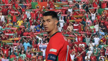 Cristiano Ronaldo looks back with a Portugal jersey on and in the background is Portuguese fans. (Source: Getty Images)
