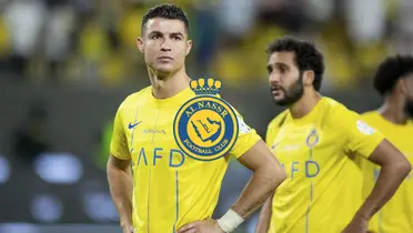 Cristiano Ronaldo looks disappointed while his hands are on his hips; the Al Nassr badge is in the middle.