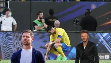Cristiano Ronaldo looks down on the ground wearing an Al Nassr kit while Xabi Alonso and David Beckham is next to him.
