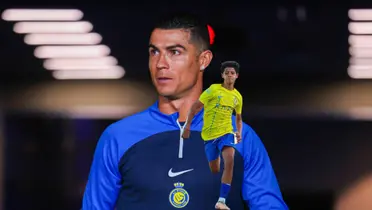 Cristiano Ronaldo looks out onto the pitch while Cristiano Ronaldo Jr. runs for the ball.