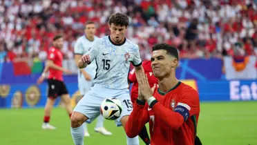 João Neves looks at the ball while Cristiano Ronaldo puts his hands together with the Portugal jersey on. (Source: Getty Images)