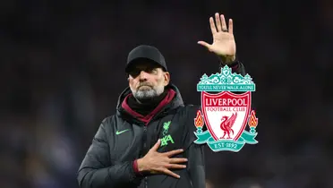 Jurgen Klopp salutes the fans in the crowd while the Liverpool badge is next to him.