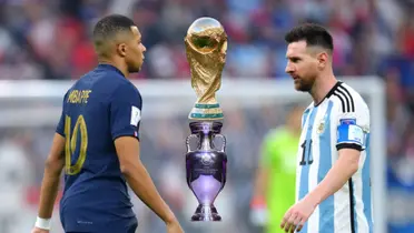 Kylian Mbappé and Lionel Messi looks at each other as the World Cup trophy and the European Championship trophy is in between them.
