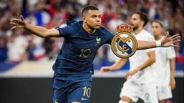 Kylian Mbappé celebrates a France goal with his arms out while wearing the blue France national team jersey; the Real Madrid badge is next to him.