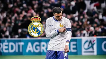 Kylian Mbappé fixes his captain arm band while wearing the France national team jersey and the Real Madrid badge is next to him.
