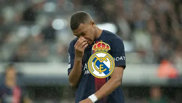 Kylian Mbappé has his hand on his nose and looks down while the Real Madrid badge is on him.
