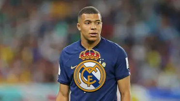 Kylian Mbappé looks to the side while wearing the French national team jersey and the Real Madrid logo is in the middle.