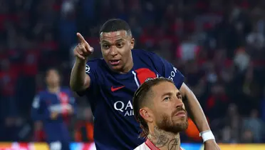 Kylian Mbappé points while wearing the PSG jersey and Sergio Ramos is serious below, wearing the Sevilla jersey.
