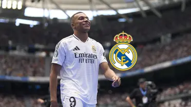 Kylian Mbappé smiles as he walks wearing the Real Madrid jersey and the Real Madrid badge is next to him. (Source: Getty Images)