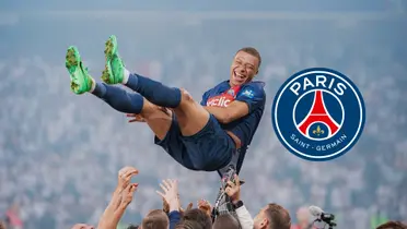 Kylian Mbappé smiles in the air as he is thrown by his PSG teammates; the PSG badge is next to him.
