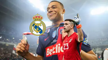 Kylian Mbappé smiles while holding a medal and Emiliano Martinez points up to the sky; the Real Madrid badge is next to him.
