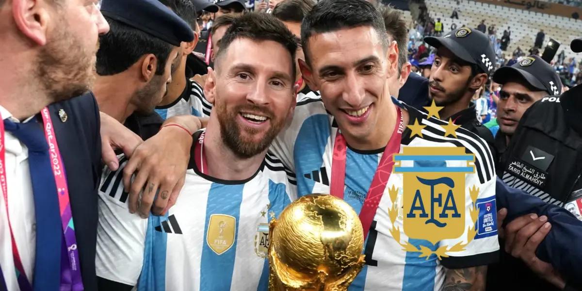 Lionel Messi and Angel Di Maria pose for a picture together with the World Cup trophy and the Argentina national team badge is next to them.