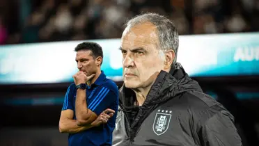 Marcelo Bielsa looks at the game with an Uruguay jacket and Lionel Scaloni has his hand on his chin.