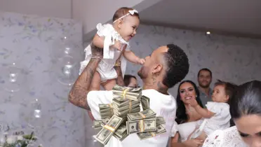 Neymar Jr. carries his daughter Mavie during the baptism party and a stack of cash is below them.