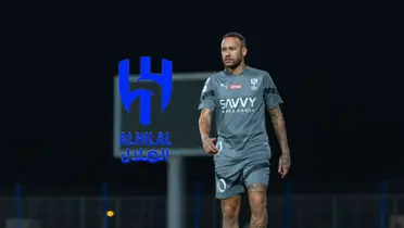 Neymar Jr is walking on the pitch wearing an Al Hilal training kit on while the Al Hilal logo is next to him.