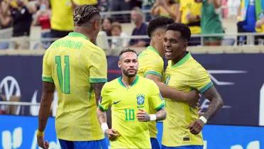 Neymar Jr. runs while wearing the Brazil jersey and the rest of the Brazilian national team players celebrate a goal together.