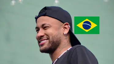 Neymar Jr. smiles while he wears a hat and the Brazil flag is next to him. (Source: Team Neymar X)