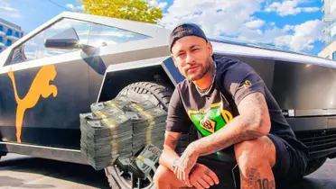 Neymar poses for a picture with the Puma Tesla Cyber Truck and a stack of $100 bills are next to him. (Source: Neymar X)