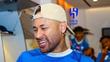 Neymar smiles while wearing a hat and the Al Hilal jersey. The Al Hilal badge is next to him.