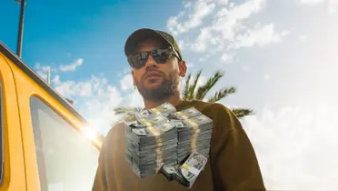 Neymar walks outside while wearing some sunglasses and there is a stack of money below him.
