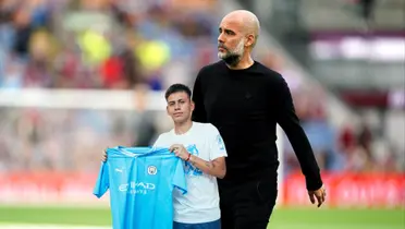 Pep Guardiola walks on the pitch while Claudio Echeverri holds the Manchester City jersey. (Source: Manchester City X)