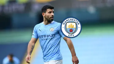 Sergio Aguero looks to his left while wearing the Manchester City jersey; the Man City badge is next to him.