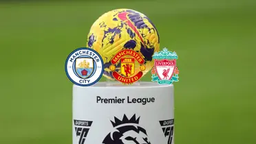 The Premier League ball is on a stand while the Manchester City, Manchester United, and the Liverpool badges are below it.