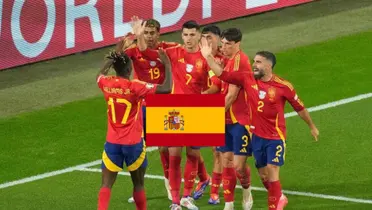 The Spanish national team celebrate a goal together while the Spanish flag is in the middle. (Source: AP Photo)