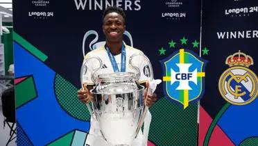 Vinicius Jr. smiles while holding the Champions League trophy while the Brazilian national team badge is next to him.