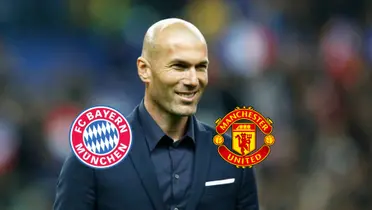 Zinedine Zidane smiles wearing a black suit with the logos of Bayern Munich and Manchester United next to him