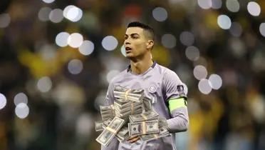 Cristiano Ronaldo on the pitch wearing an Al Nassr jersey while a stack of money is below him.