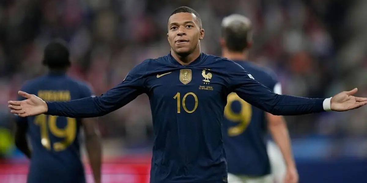 Kylian Mbappé puts his arms out wearing the France jersey.