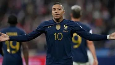 Kylian Mbappé puts his arms out wearing the France jersey.