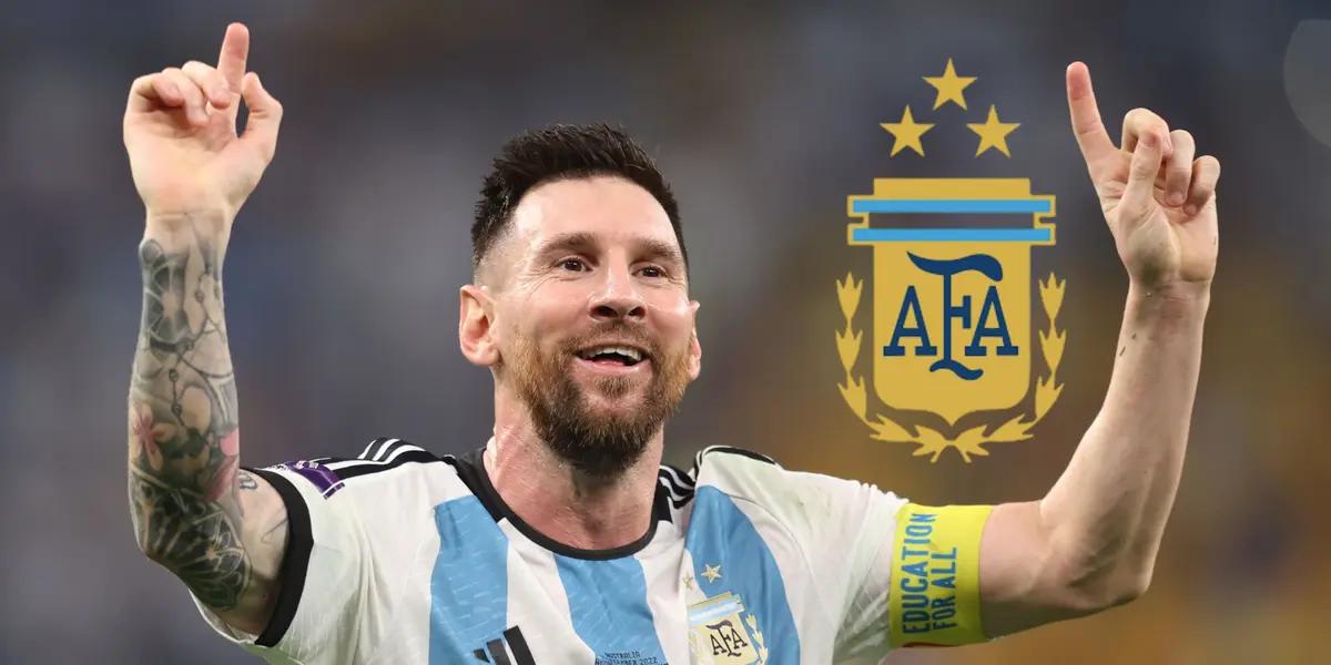 Lionel Messi smiles and points two fingers to the sky while wearing the Argentina national team jersey; the Argentina national team badge is next to him.