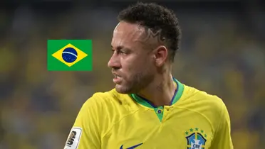 Neymar Jr. looks to his right as he wears the Brazil jersey and the Brazil flag is to the side of him. (Source: Getty Images)