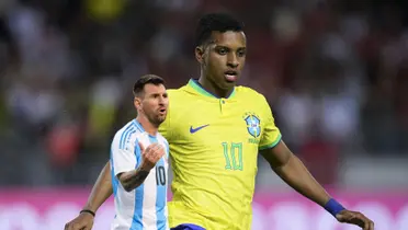 Rodrygo looks at the pitch while wearing the Brazil national team jersey and Lionel Messi looks disappointed while wearing the Argentina national team jersey.