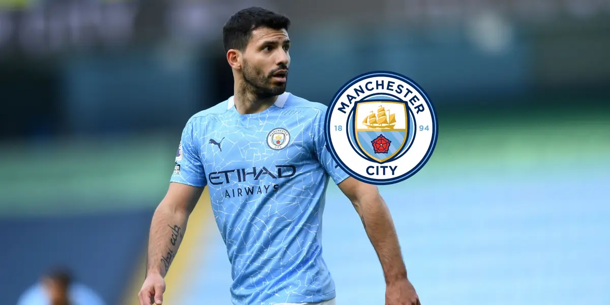 Sergio Aguero looks to his left while wearing the Manchester City jersey; the Man City badge is next to him.